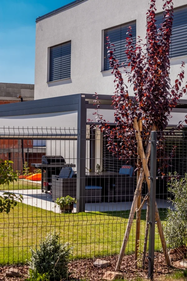 Exteriér – Rodinný dům Dolní Počernice, zastřešená terasa s venkovním posezením a grilem za plotem