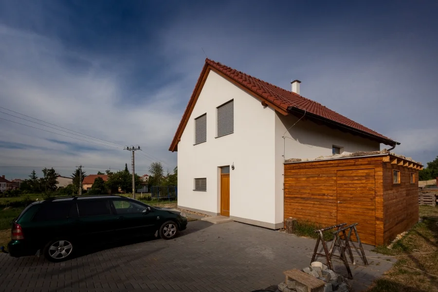 Exteriér – Rodinný dům Sokolnice, čelní pohled s vysokou sedlovou střechou a dřevěnou přístavbou garáže